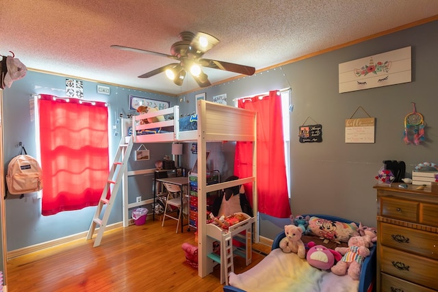 bedroom with hardwood / wood-style flooring, ceiling fan, crown molding, and a textured ceiling