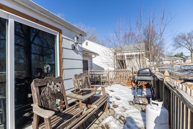 snow covered patio with a wooden deck and a grill