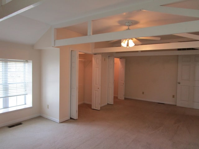 unfurnished bedroom with light colored carpet, lofted ceiling, visible vents, and two closets
