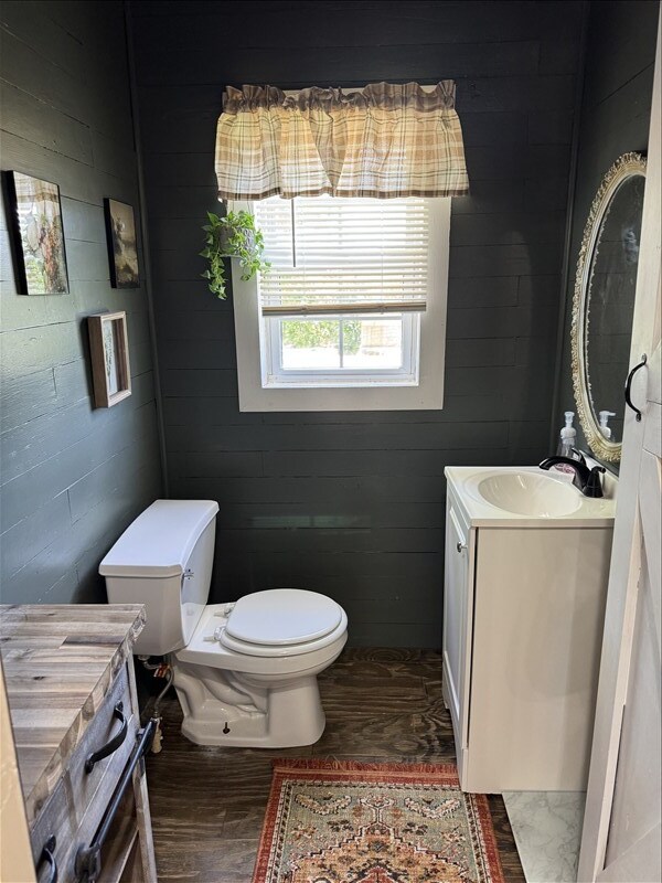 411 S Macon St, Bevier, MO 63532 - half bathroom with wood finished floors, vanity, and toilet