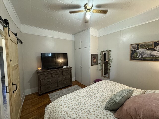 411 S Macon St, Bevier, MO 63532 - bedroom featuring a barn door, dark wood-style floors, ornamental molding, a ceiling fan, and baseboards