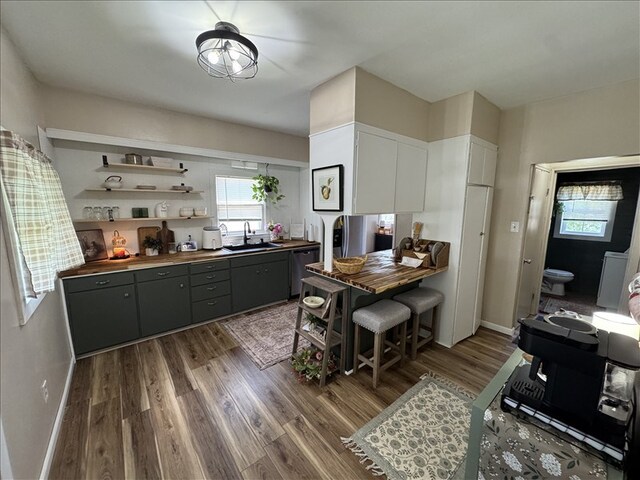 411 S Macon St, Bevier, MO 63532 - kitchen featuring wooden counters, wood finished floors, a sink, stainless steel dishwasher, and white cabinets