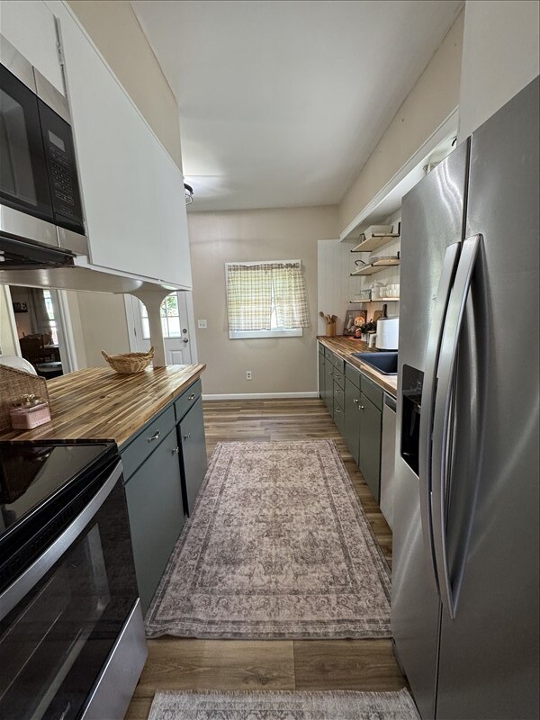 411 S Macon St, Bevier, MO 63532 - kitchen featuring stainless steel appliances, wooden counters, light wood finished floors, baseboards, and open shelves
