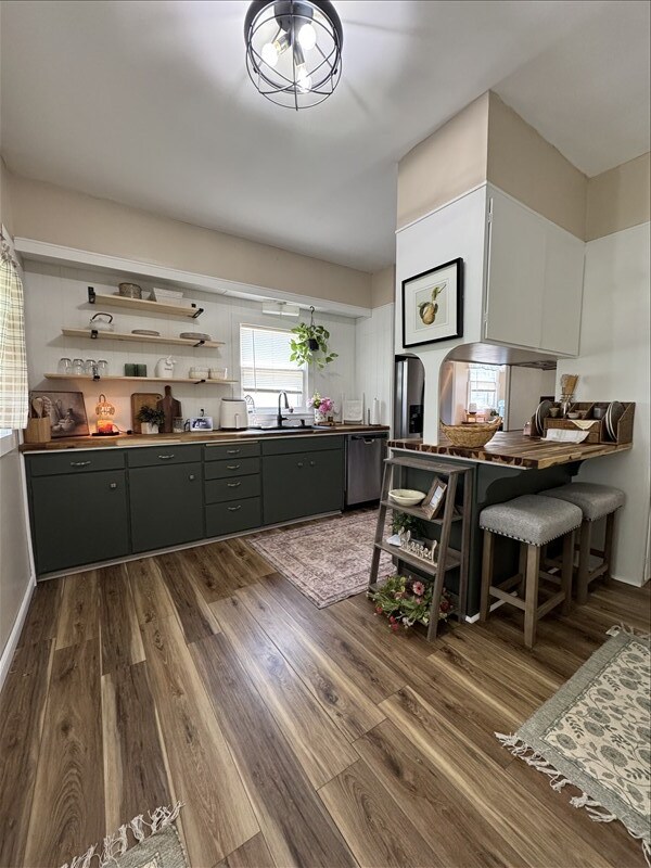 411 S Macon St, Bevier, MO 63532 - kitchen featuring open shelves, dark wood-style flooring, dark countertops, dishwasher, and a sink
