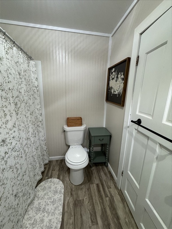 411 S Macon St, Bevier, MO 63532 - full bath featuring wood finished floors, toilet, baseboards, and a shower with curtain