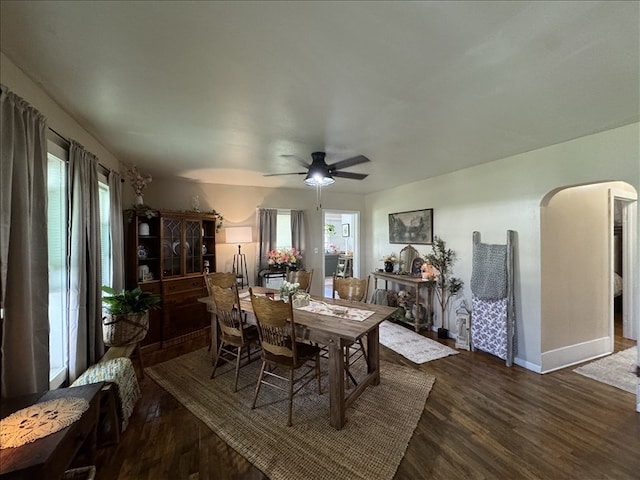 411 S Macon St, Bevier, MO 63532 - dining space featuring arched walkways, dark wood-type flooring, a ceiling fan, and baseboards