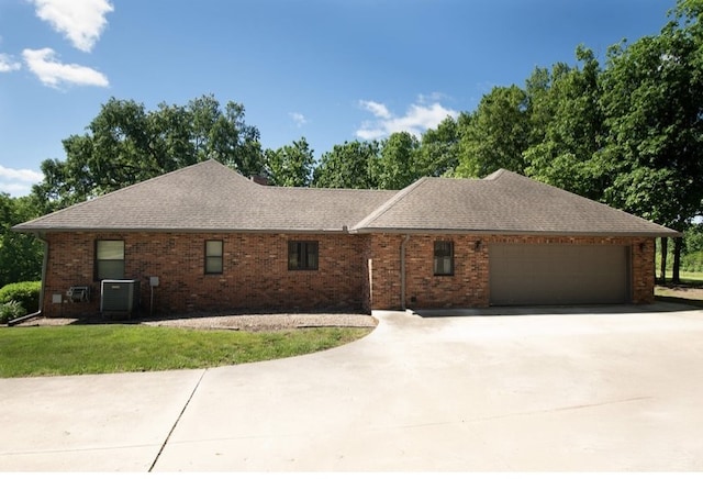 2110 Woodcrest Dr, Chillicothe, MO 64601 - view of front of house with cooling unit, driveway, an attached garage, roof with shingles, and brick siding
