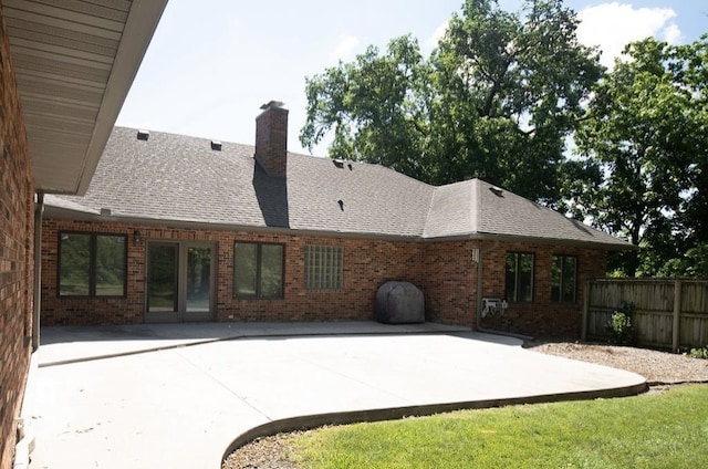 2110 Woodcrest Dr, Chillicothe, MO 64601 - back of property with brick siding, a patio area, a chimney, and a shingled roof