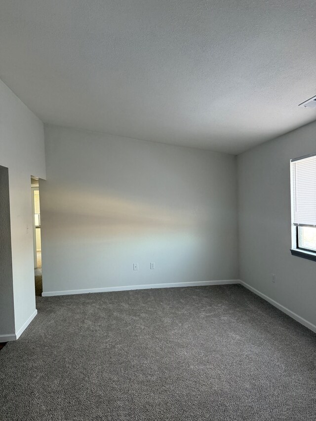 706 Woodwinds Ct, Kirksville, MO 63501 - empty room with visible vents, baseboards, a textured ceiling, and dark carpet