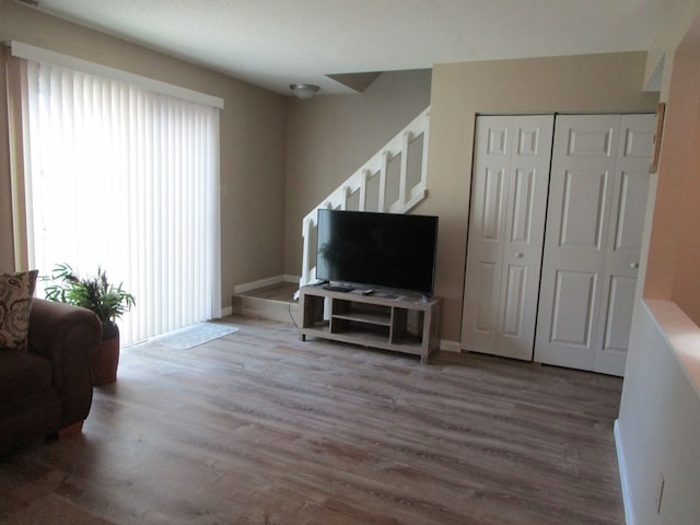 living area with baseboards, stairway, and wood finished floors