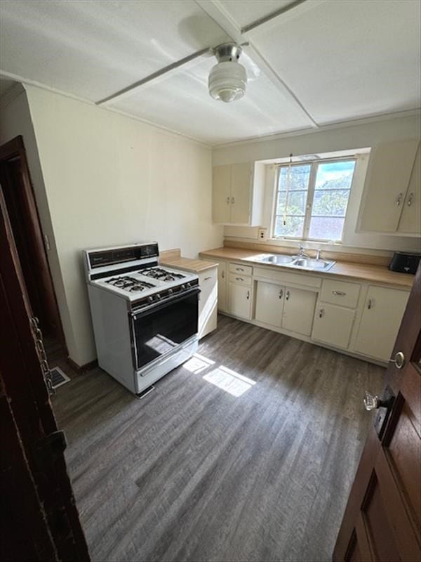 kitchen with dark wood-type flooring, sink, white gas range oven, ceiling fan, and white cabinetry