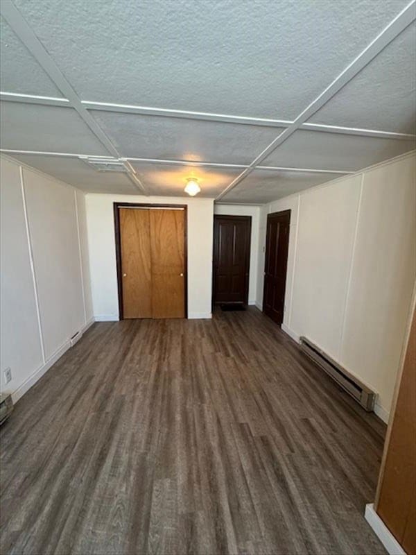 unfurnished bedroom with dark hardwood / wood-style floors, a baseboard radiator, and coffered ceiling