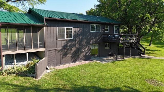 rear view of house featuring a sunroom, a yard, a patio, and a deck