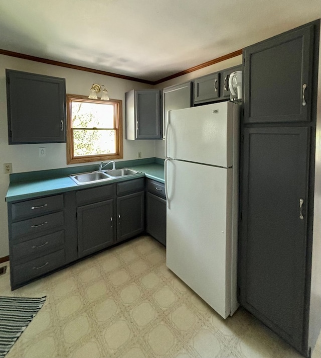 kitchen featuring white fridge, ornamental molding, and sink