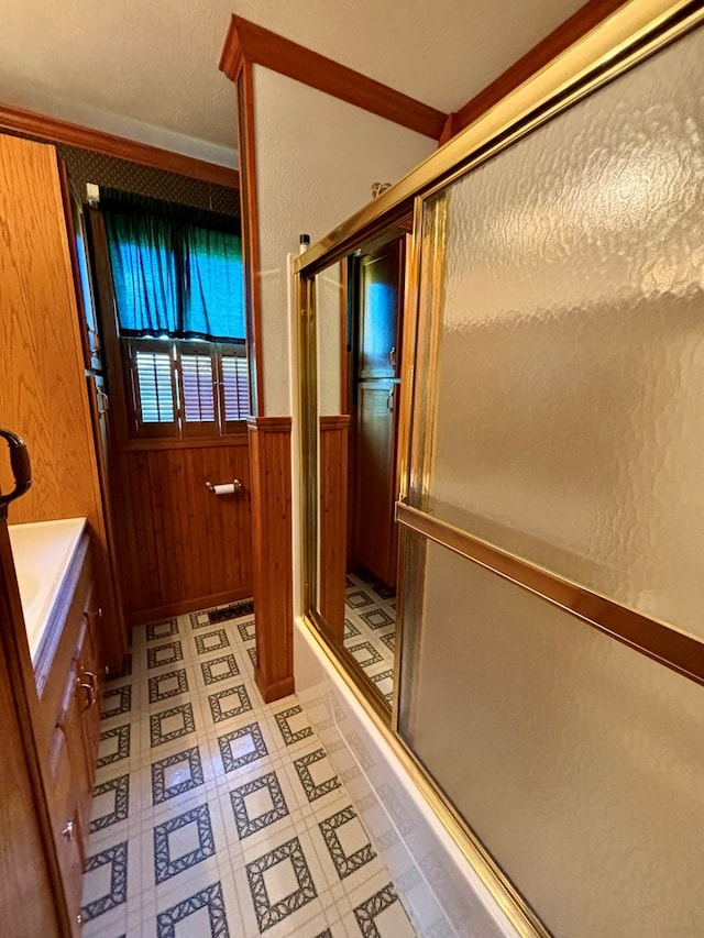 bathroom featuring vanity, a shower with door, ornamental molding, and wood walls