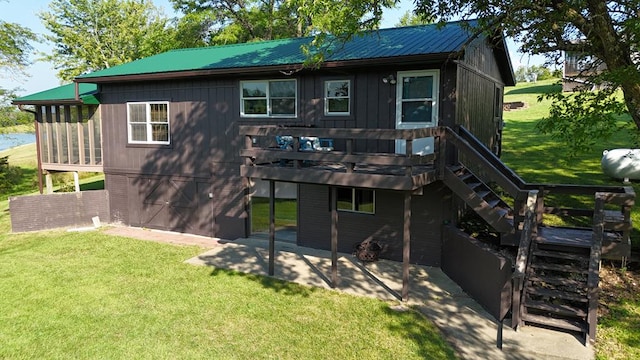 back of property with a wooden deck, a sunroom, a yard, and a patio