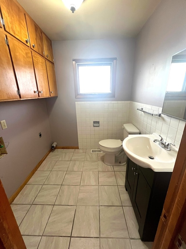 bathroom with vanity, tile walls, and toilet