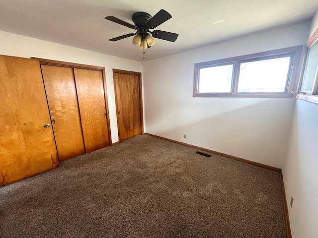 unfurnished bedroom featuring two closets, ceiling fan, and carpet