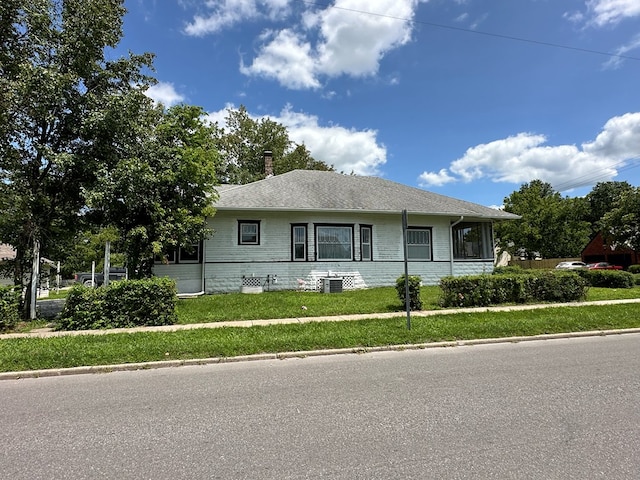 view of front of home with central AC unit and a front yard