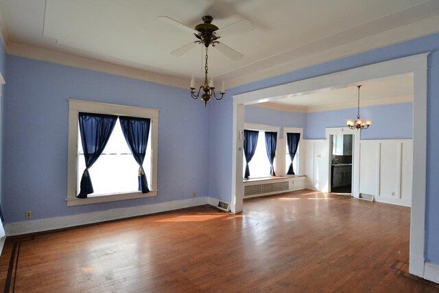 spare room with ceiling fan with notable chandelier, hardwood / wood-style flooring, and radiator