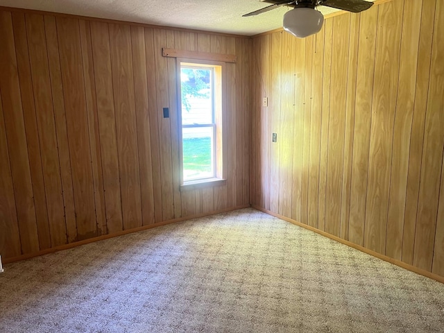 carpeted spare room with ceiling fan and wooden walls