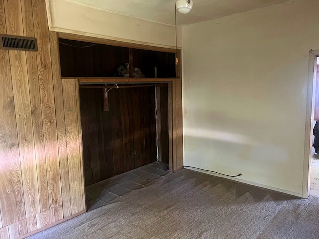 empty room featuring carpet floors and wood walls