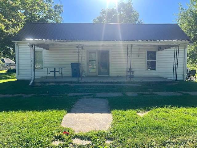 rear view of property featuring a lawn and a porch