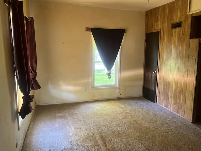 carpeted spare room featuring wooden walls