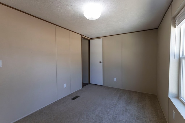 1018 Logue Ln, Keytesville, MO 65261 - spare room featuring carpet flooring, visible vents, a textured ceiling, and ornamental molding