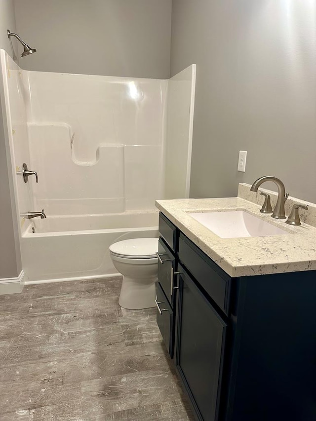 full bathroom with  shower combination, toilet, vanity, and wood-type flooring