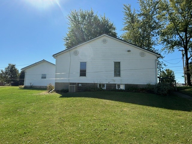 view of side of property featuring a yard and central AC