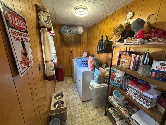 clothes washing area featuring washer and clothes dryer and wooden walls