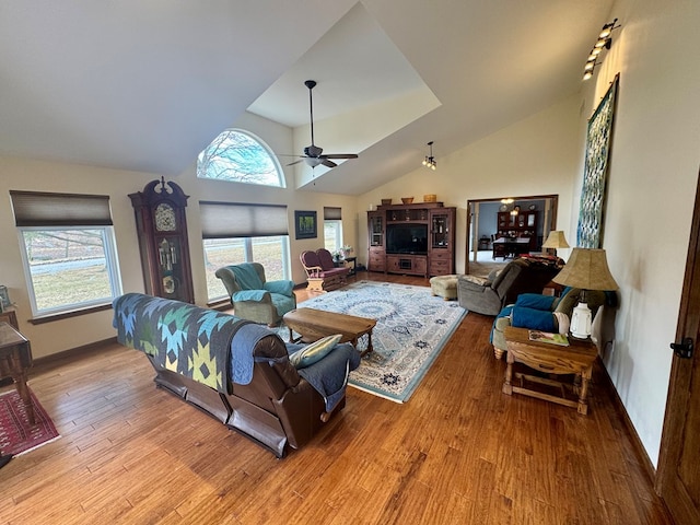 living room featuring baseboards, high vaulted ceiling, wood finished floors, and a ceiling fan