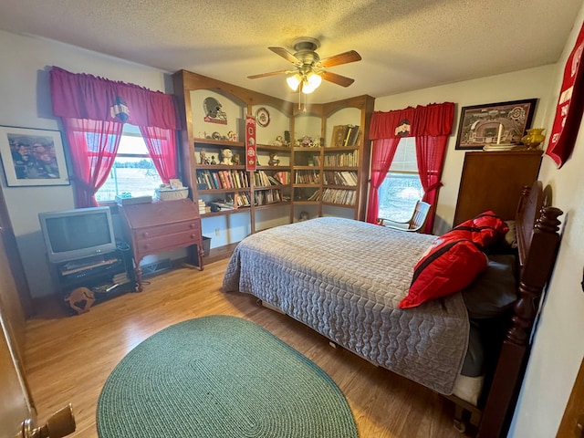 bedroom with a textured ceiling, wood finished floors, and a ceiling fan