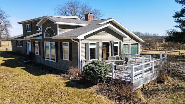 exterior space featuring a shingled roof, a front lawn, fence, a chimney, and a deck
