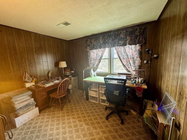 office area featuring visible vents, carpet floors, a textured ceiling, and wooden walls