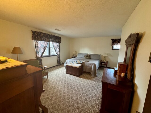 carpeted bedroom with baseboards, visible vents, and a textured ceiling