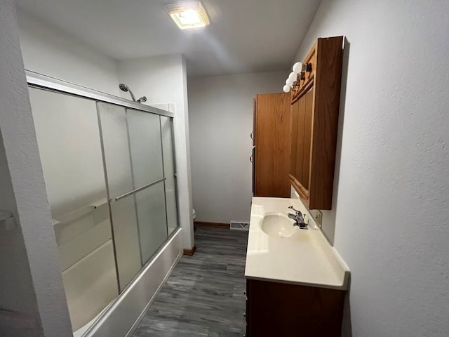 full bathroom with hardwood / wood-style flooring, vanity, toilet, and combined bath / shower with glass door