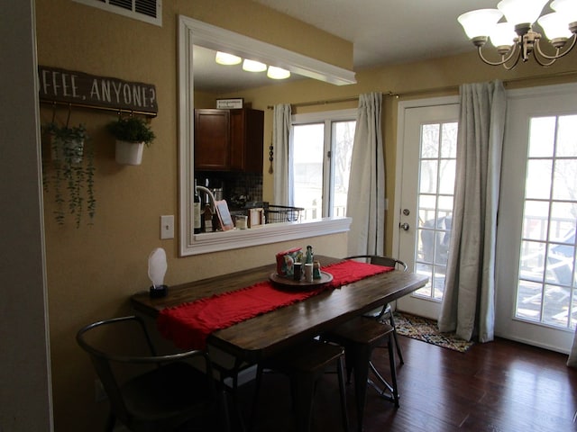 dining space featuring a healthy amount of sunlight, dark hardwood / wood-style floors, and an inviting chandelier