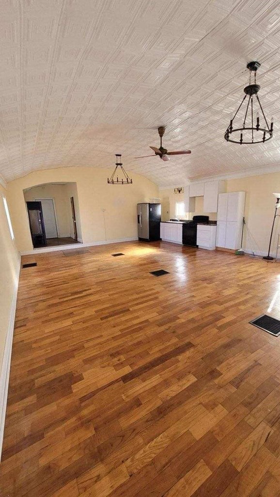 unfurnished living room featuring ceiling fan, wood-type flooring, and brick ceiling