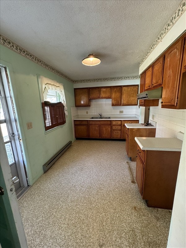 kitchen with baseboard heating, decorative backsplash, sink, and a textured ceiling