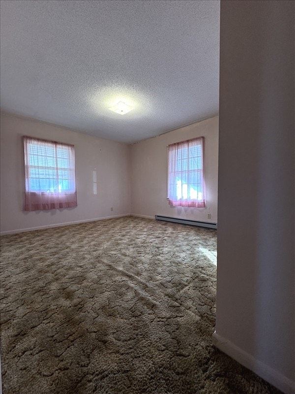 empty room with carpet, a baseboard radiator, and a textured ceiling