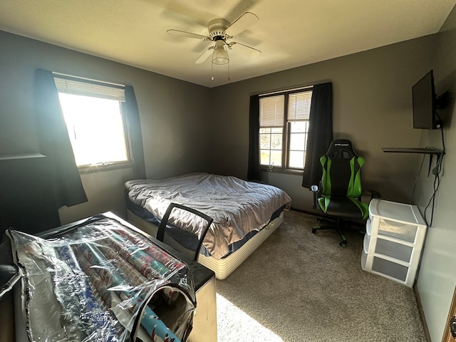 bedroom featuring ceiling fan, light colored carpet, and multiple windows