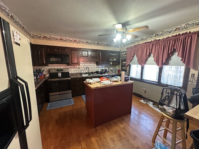 kitchen with decorative backsplash, dark brown cabinetry, wood-type flooring, a center island, and stainless steel electric range oven