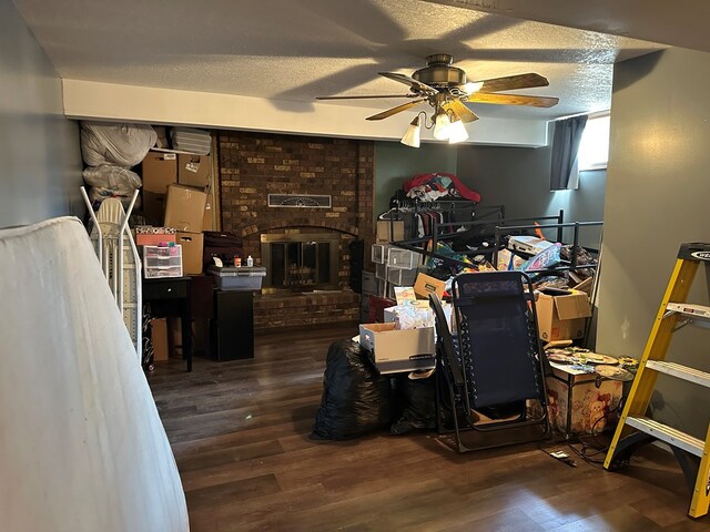 interior space with ceiling fan, dark hardwood / wood-style flooring, a textured ceiling, and a brick fireplace