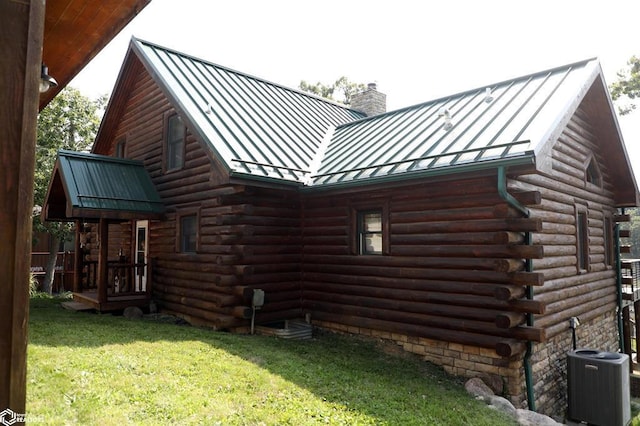 view of side of property with central AC unit, a standing seam roof, a lawn, and log exterior