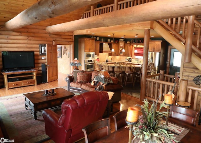 living area featuring light wood-style floors, a high ceiling, log walls, and beam ceiling