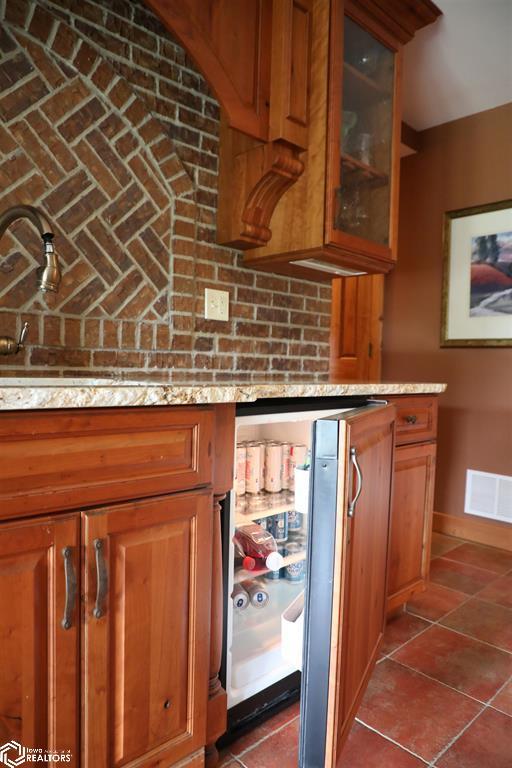 interior space featuring a bar, dark tile patterned flooring, visible vents, and baseboards