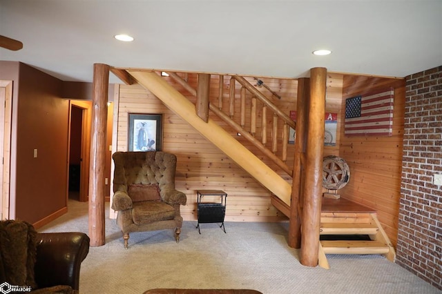 sitting room featuring stairs, carpet, wood walls, and recessed lighting