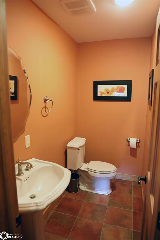 half bathroom featuring baseboards, visible vents, a sink, and toilet